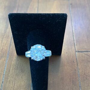 10 KT CUBIC ZIRCONIA ROUND IN 925 STERLING SILVER BAND. 2 BAQUETTES EACH SIDE.